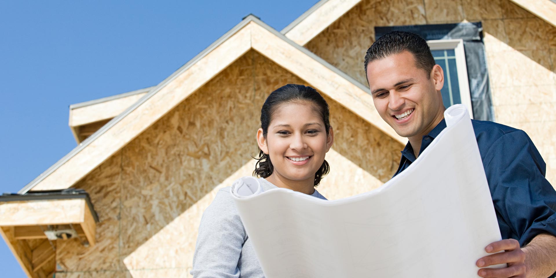 Two young homeowners looking at blueprints who have financed home improvements with a Home Equity Line