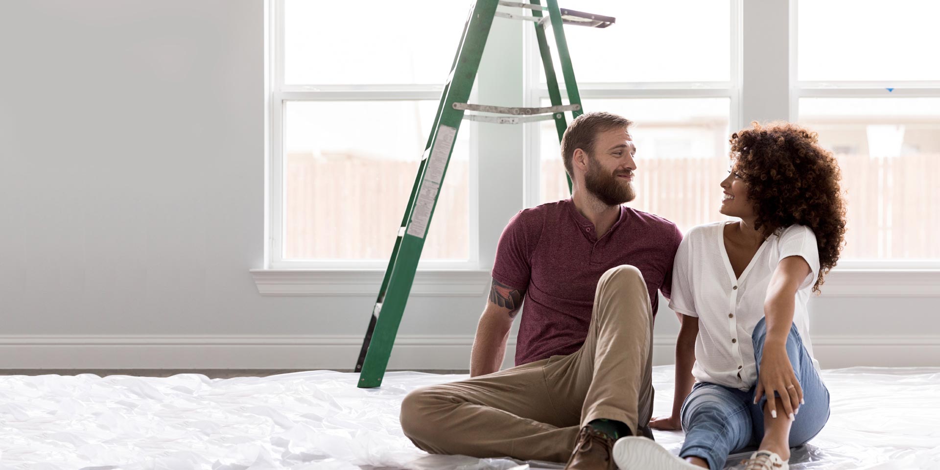 A diverse young couple site under a ladder during a remodeling project financed by a Home Improvement Loan