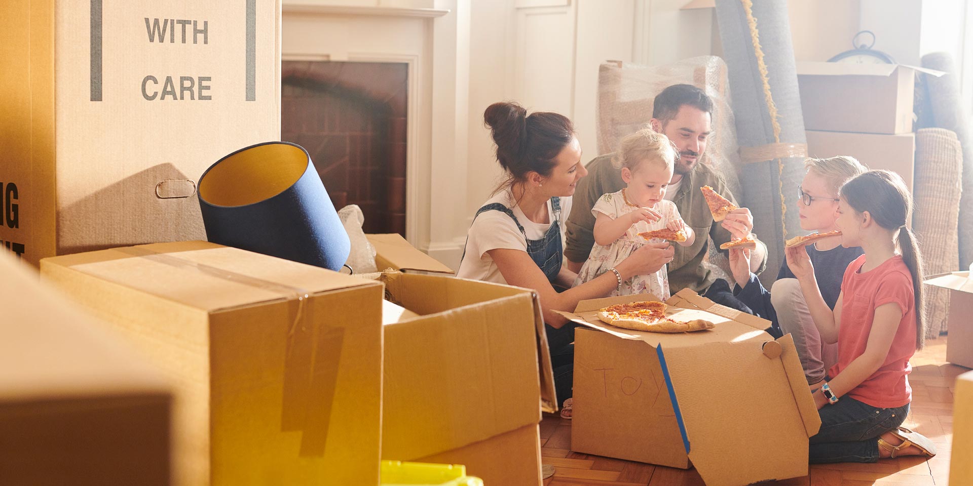 A family of five who recently received a mortgage is eating pizza as they move into their new home