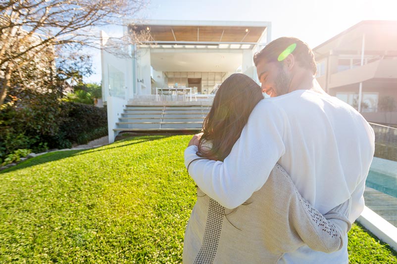 Younger couple in front of a home they hope to purchase and would like to calculate their payment