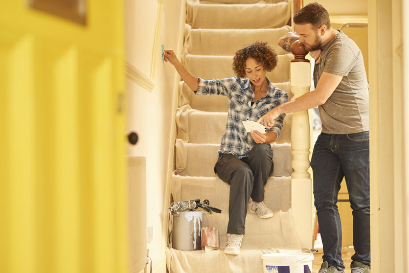 A diverse couple are choosing paint colors for a project that will need a Home Equity Loan or Line of Credit