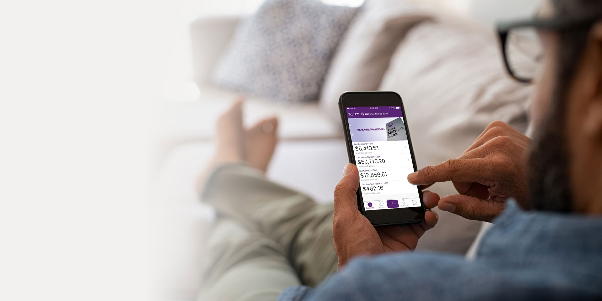 A relaxed man uses the mobile banking app to view his online bank account information