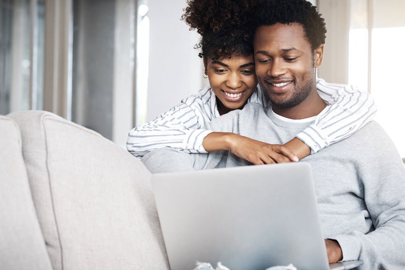 A couple is relaxing on a couch while reading about identity theft prevention and cyber security on a laptop