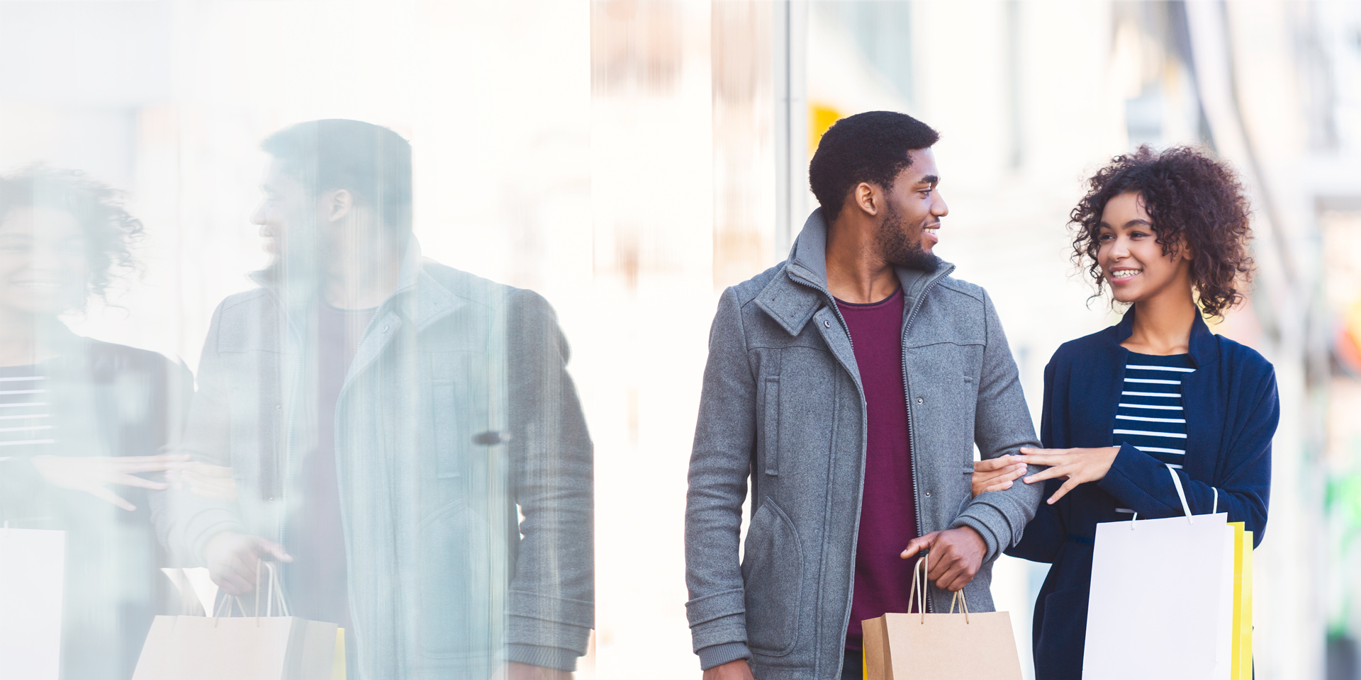 A young couple holding shopping bags.