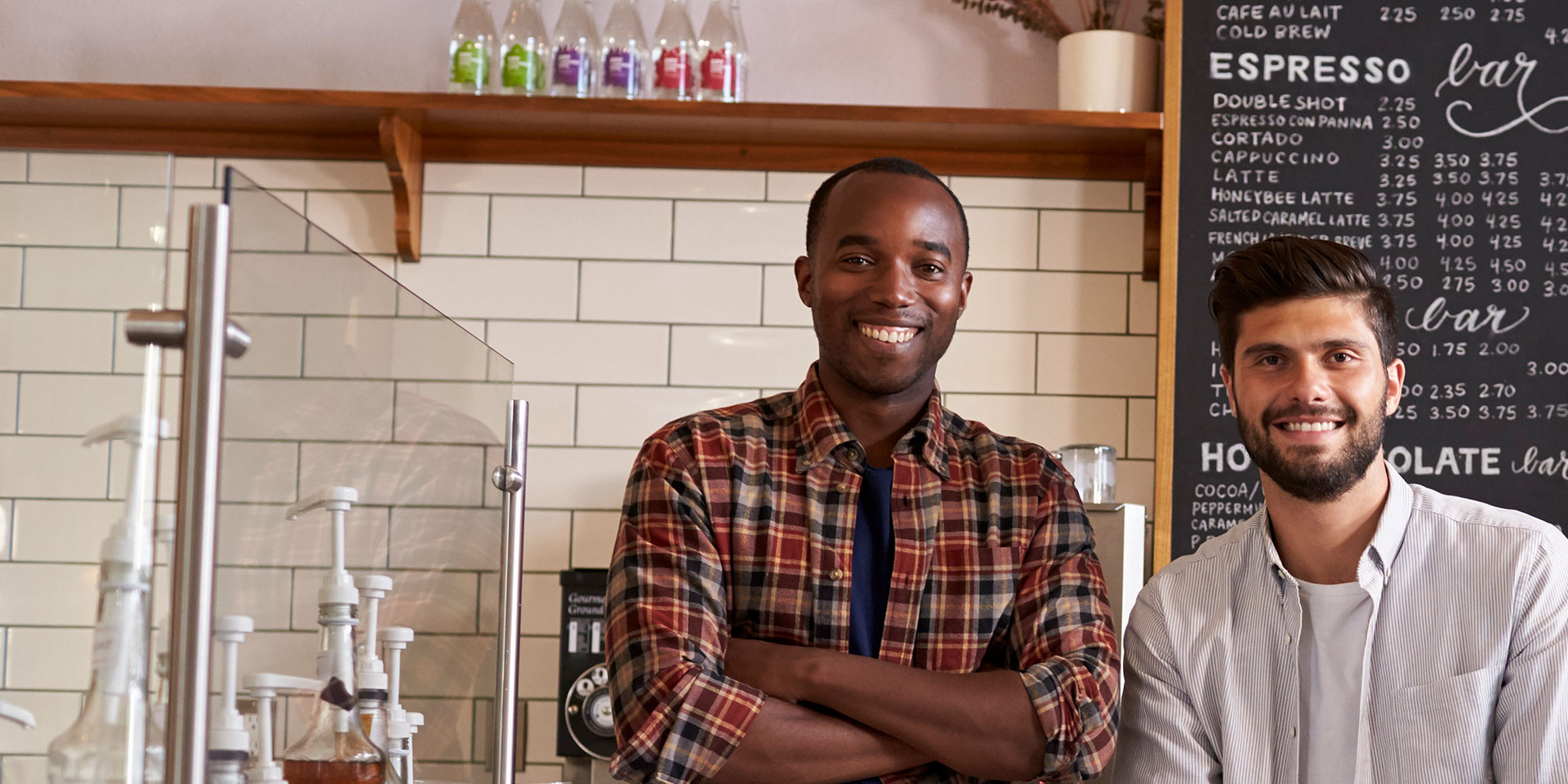 Co-owners of a coffee shop stand together smiling after opening an Essential Business Checking account